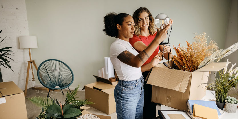 Two women looking through cardboard boxes in the lounge, deciding what to keep.