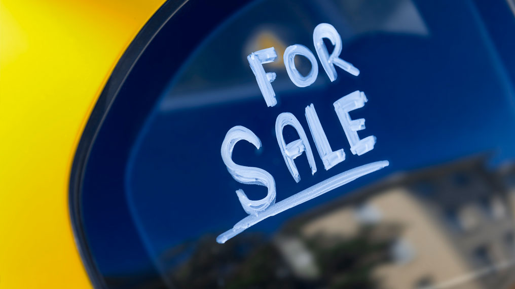 a yellow car with "for sale" written on the windscreen