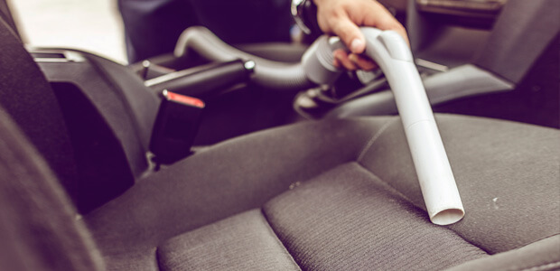 Car interior being cleaned with hoover