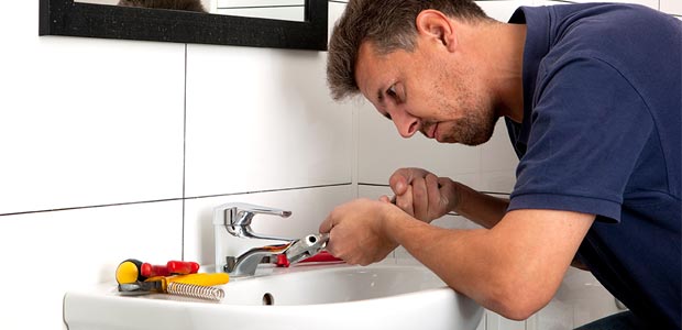 Man fixing leaky tap with a spanner