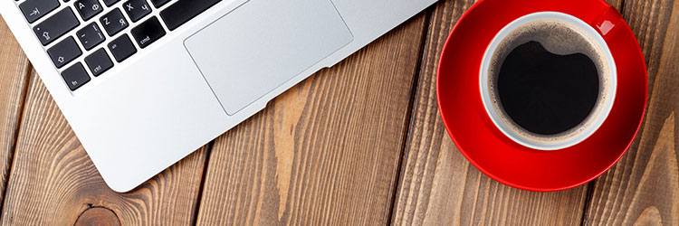 Coffee and laptop on a wooden desk