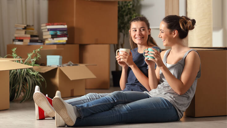 Friends relax with a cup of tea after moving into a shared home.